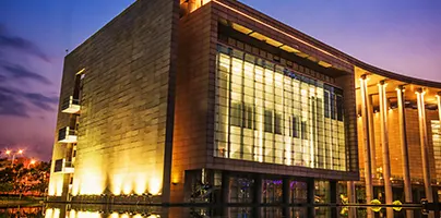 Modern building with large glass windows and illuminated exterior at dusk.